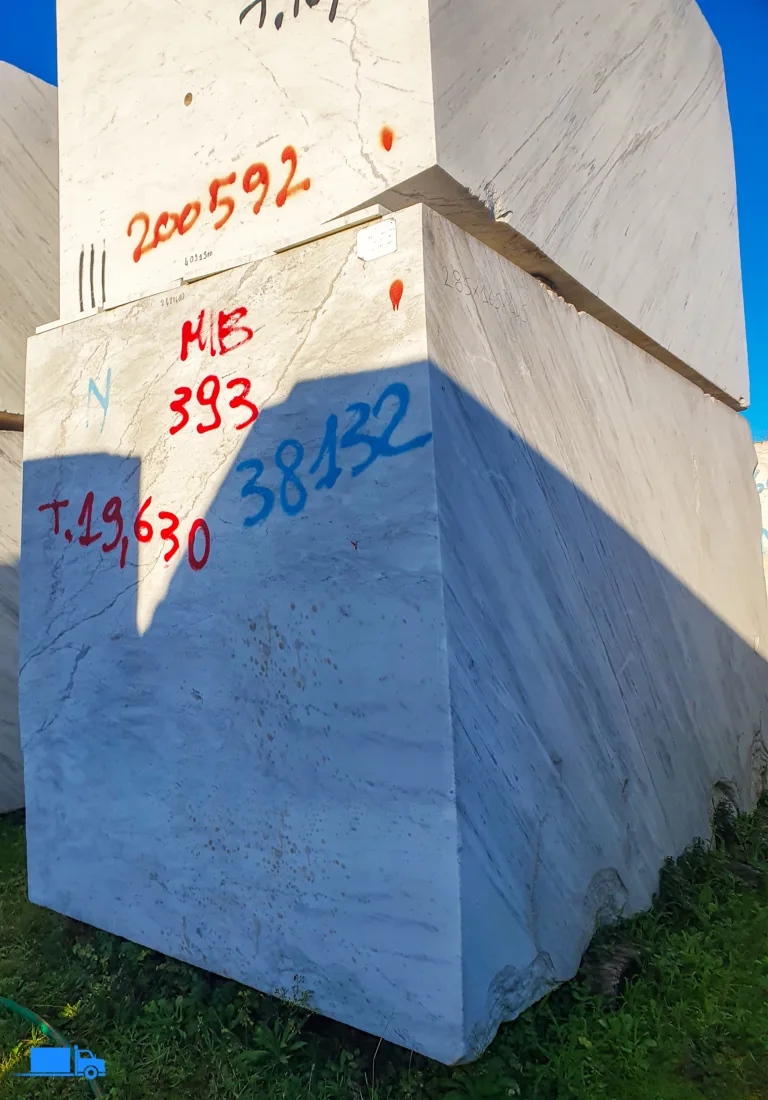 Bloki marmurowe z czerwonymi oznaczeniami, ułożone w magazynie